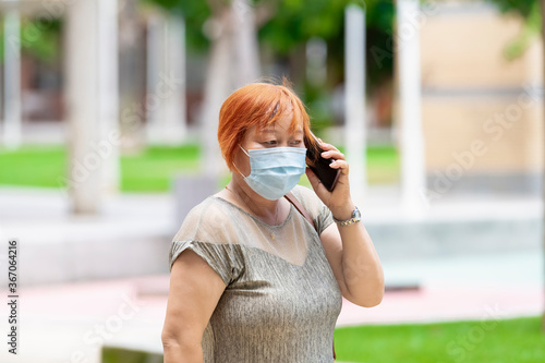 asian woman wearing a surgical mask talking on her phone outdoors . Safety and communication concept. photo