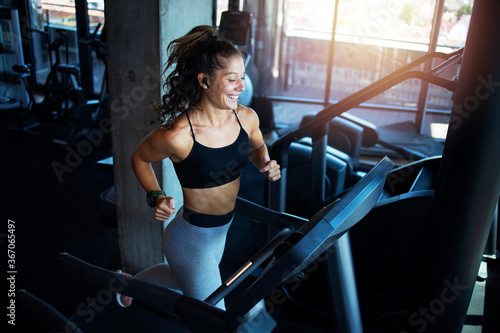 Obraz na plátně Top view of smiling woman exercising and training in the gym on treadmill running machine