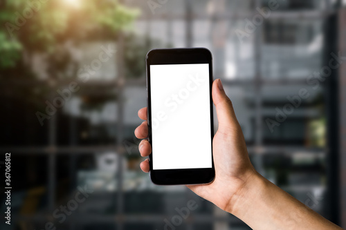 Hand holding white mobile phone with blank white screen in cafe.