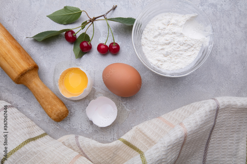 Ingredients baking flour eggs rolling pin berries kitchen textiles on gray background. Cookie pie or cake recipe mockup. Background preparation for culinary baking. Ingredients baking flour eggs rolling pin berries kitchen textiles on gray background. Cookie pie or cake recipe mockup. Background preparation for culinary baking.