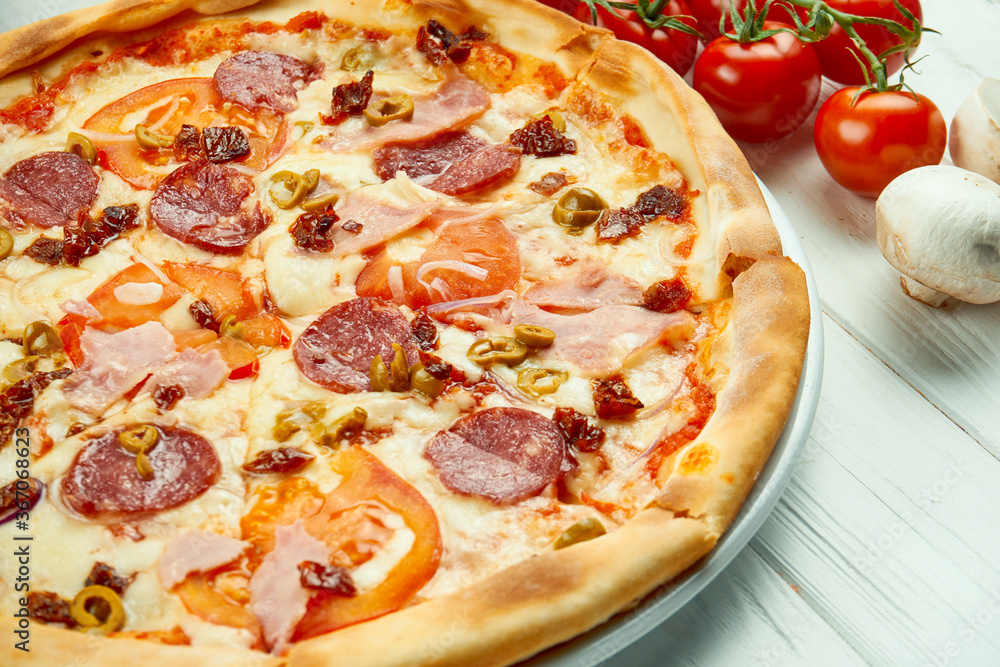 Italian pizza with salami, ham and olives in a composition with ingredients on a white background