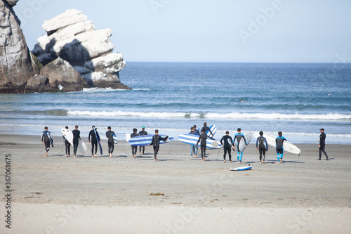 Photography Large group of surfers standing on the beach ready to go surfing with their surf