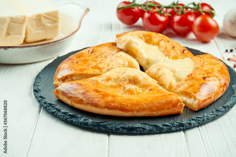 Close up view on tasty traditional Khachapuri - closed baked pie stuffed with melted salt cheese (suluguni). georgian food