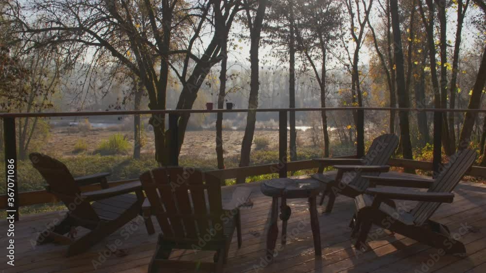 Rustic cabin in a forest with a wooden deck and chairs Rustic cabin in a forest with a wooden deck and chairs