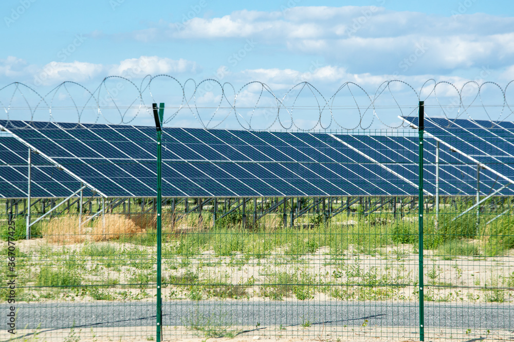 Alternative energy source, solar panels, green energy. Behind a metal fence with barbed wire. Alternative energy source, solar panels, green energy. Behind a metal fence with barbed wire.