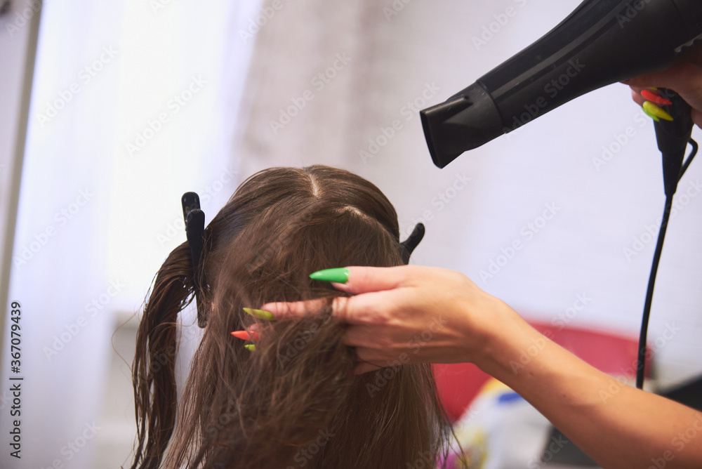 Naklejka premium hair drying with a hair dryer in a barbershop. Master universal dry and comb the hair hair