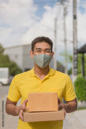 Delivery man wearing face mask in yellow uniform. newnormal lifestyle after Coronavirus pandemic. photo