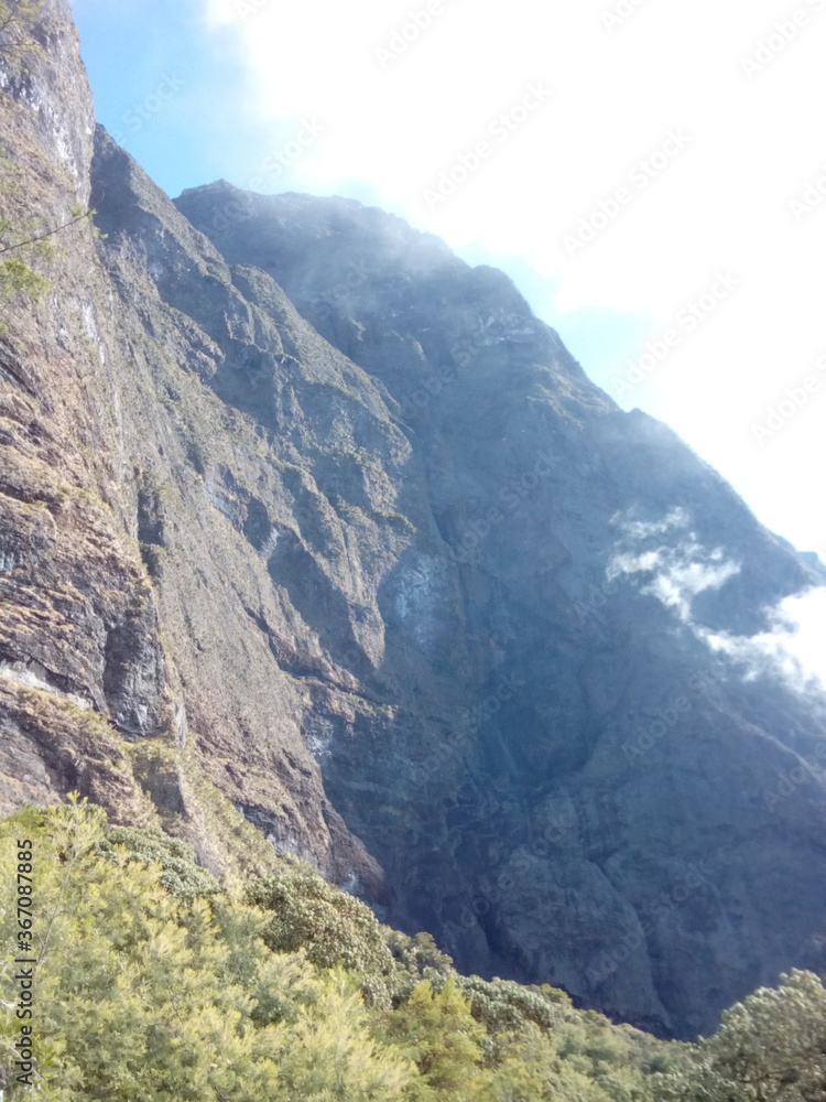Rock climb wall, cloud over top mountain peak, daylight square human face shape