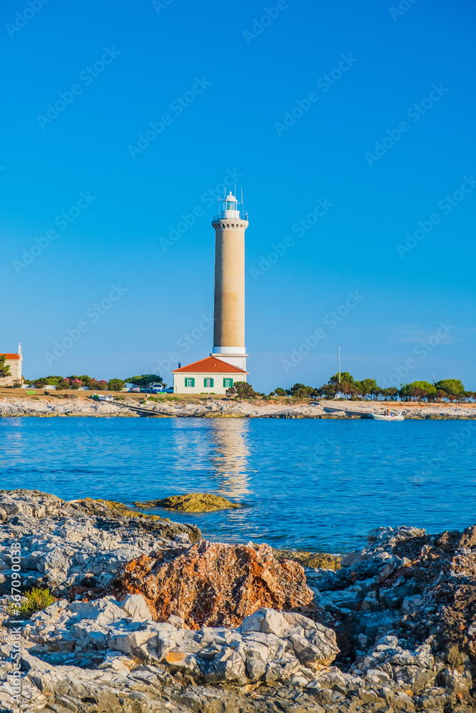 Lighthouse of Veli Rat on the island of Dugi Otok, Croatia, beautiful Adriatic seascape and rocks in foreground