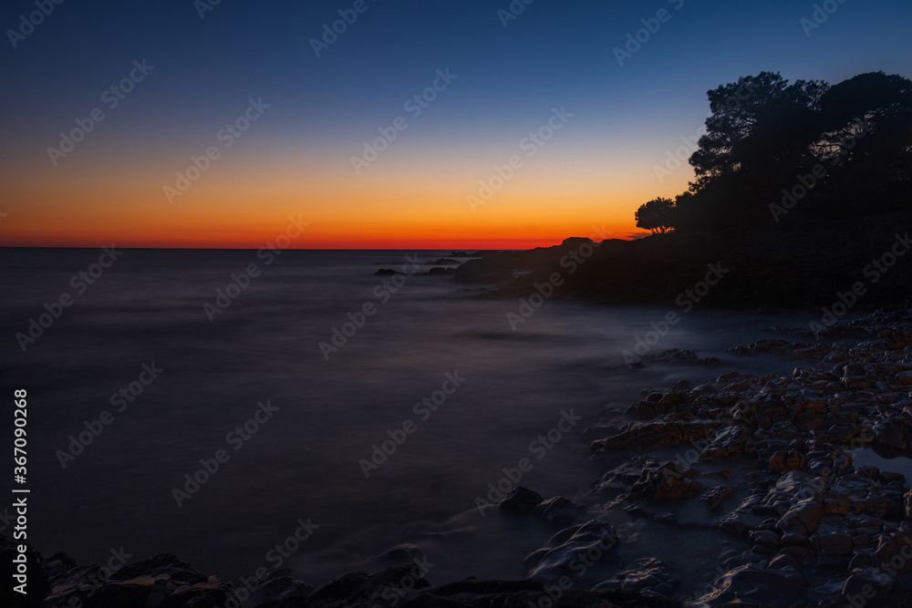 Beautiful evening on Adriatic Sea in Croatia, waves on rocks on shore of Dugi Otok island. Amazing sea sunset and red sky on horizon. Long exposure.
