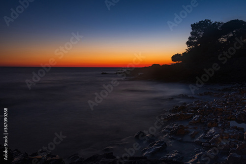 Beautiful evening on Adriatic Sea in Croatia, waves on rocks on shore of Dugi Otok island. Amazing sea sunset and red sky on horizon. Long exposure. 