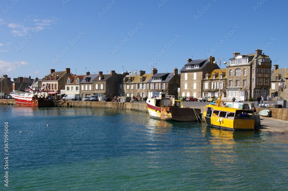Fishing harbour, boats and terraced seaside cottages on a sunny day in Barfleur, Normandy, France.
