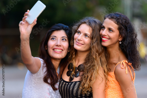 Three young beautiful women as friends together outdoors