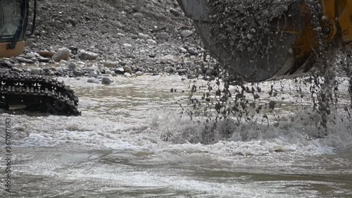 Close up excavator digging sand pebbles from the river. Heavy industry and environment. Ecological disaster. Water pollution. Machine dredging river canal. Dam building. Slow motion, static shot