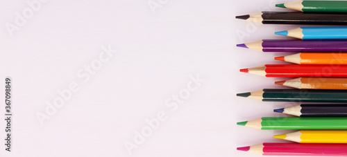 Colored pencils on a white background in staggered order. Lots of different colored pencils. Colored pencil. Pencils are sharp. Pencils on the left. Close-up. Copy space. Background. Flat lay. Banner
