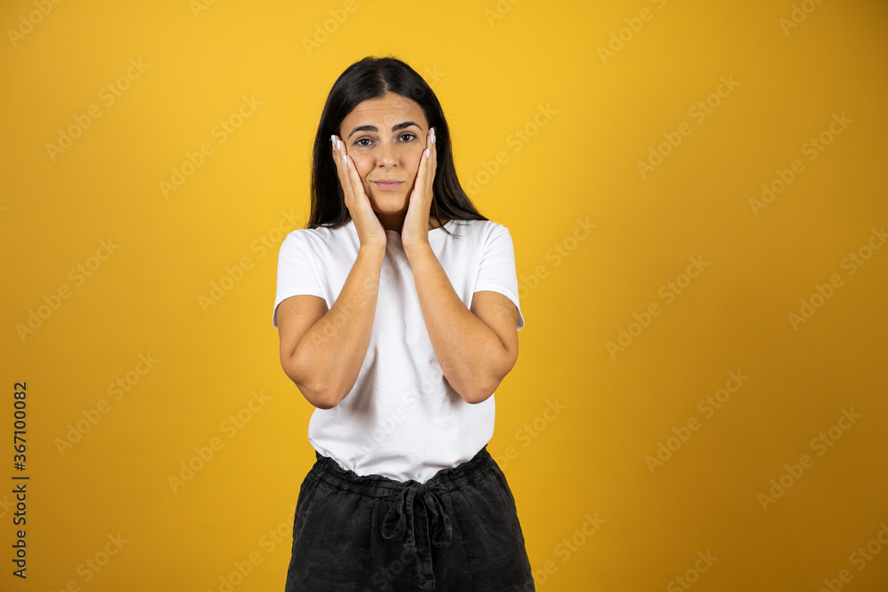 Young beautiful woman standing over isolated yellow background suffering from headache desperate and stressed because pain and migraine with her hands on head Young beautiful woman standing over isolated yellow background suffering from headache desperate and stressed because pain and migraine with her hands on head