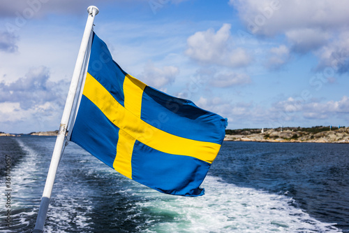The Swedish flag flying in the wind on a boat cruising the Swedish archipelago, Sweden