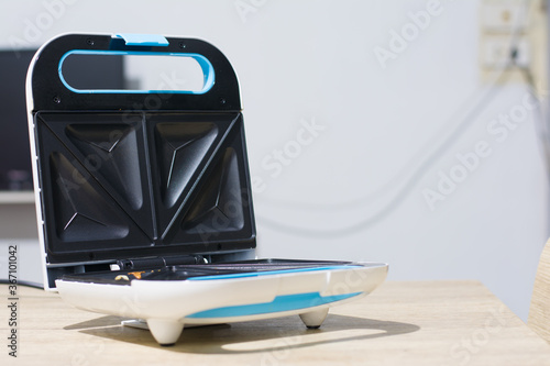Toaster with dishes and sandwiches on a light kitchen table,Toaster with bread slices on kitchen table
