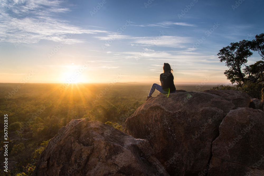 Girl looking over landscape at sunrise 