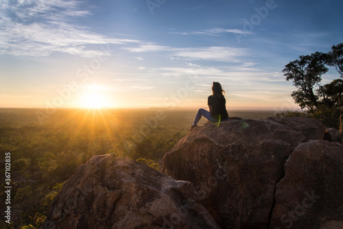 Girl looking over landscape at sunrise 