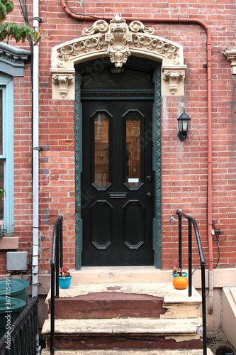 Vintage shabby-looking entry door in New York decorated with arch and corbels. USA.