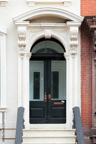 Vintage shabby-looking entry door in New York decorated with arch and corbels. USA.