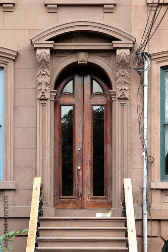 Vintage shabby-looking entry door in New York decorated with arch and corbels. USA.