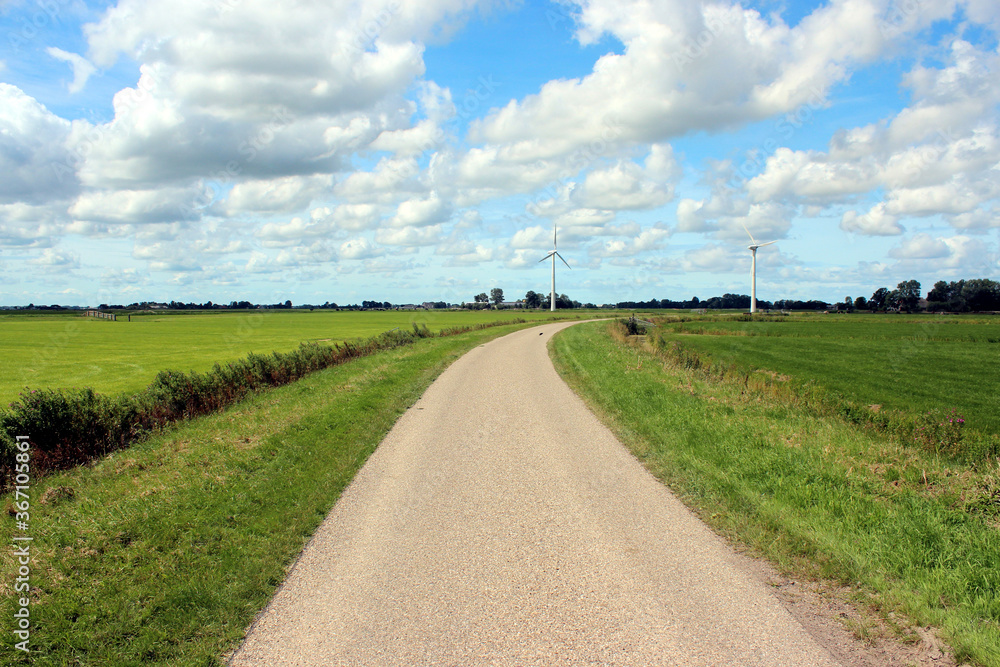 Rural landscape with windmills and country road in the Netherlands. Photo was taken on a beautiful sunny day with and clear blue sky.