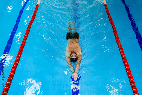 Obraz na płótnie Man swimmer swims backstroke in the swimming pool