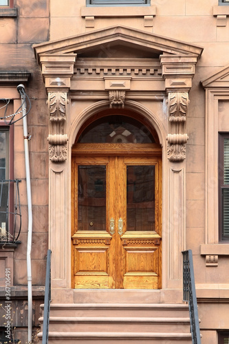 Double wooden vintage arched entry door decorated with arch, corbels and pilasters. New York. USA.