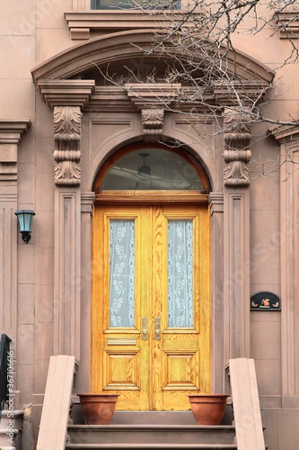 Double wooden vintage arched entry door decorated with arch, corbels and pilasters. New York. USA.