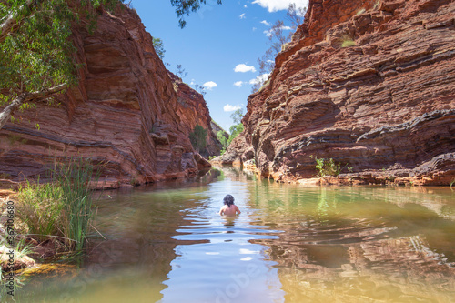 A man is swimming in Mamersley Gorge in Karijini National Park, Western Australia 