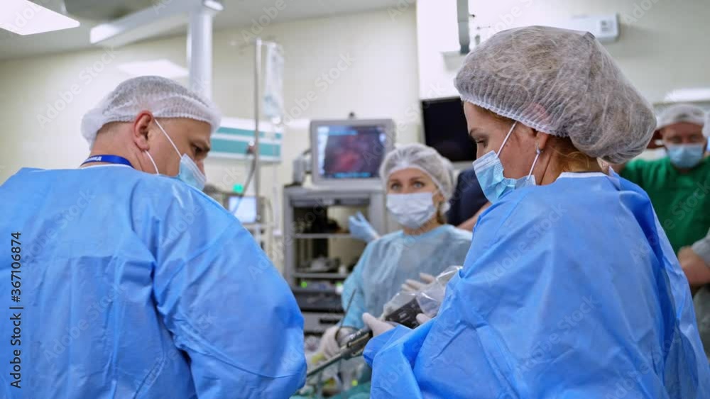 Modern surgery. Teamwork of doctors in the operating room. Professional female surgeon in medical mask and uniform works with surgical tools. Modern surgery. Teamwork of doctors in the operating room. Professional female surgeon in medical mask and uniform works with surgical tools.
