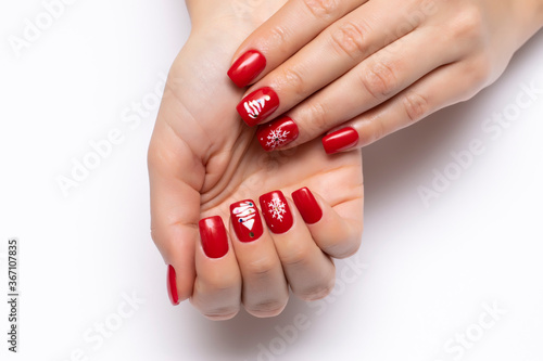  New Year's red manicure with painted white snowflakes and a Christmas tree on short square nails on a white background close-up