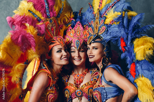 Fototapeta Three Women smiling portrait in brazilian samba carnival costume with colorful feathers plumage