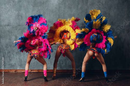 Three Woman in brazilian samba carnival costume with colorful feathers plumage. photo