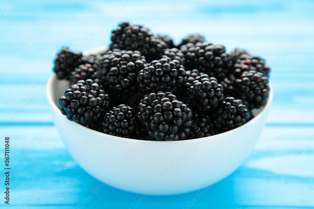 Blackberries in a bowl on blue wooden table. Blackberries in a bowl on blue wooden table.