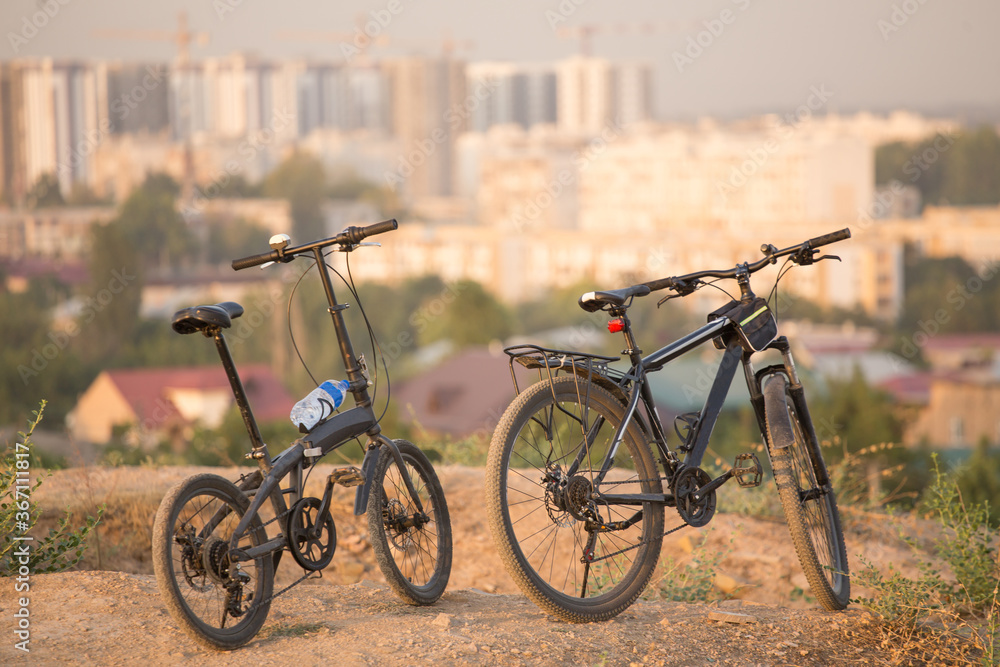 two bicycles stand on the mountain against the background of the city