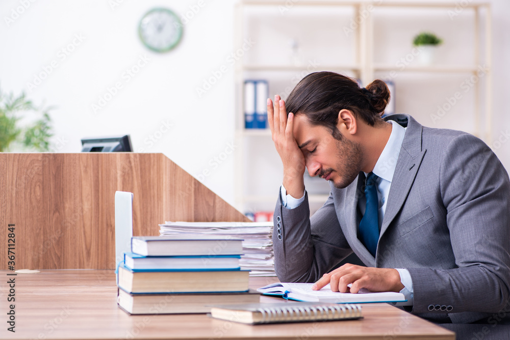Young male businessman reading books at workplace Young male businessman reading books at workplace