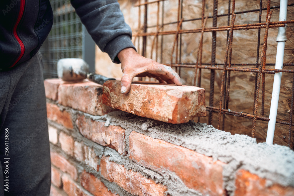 Close up of industrial bricklayer installing bricks on construction site. Construction works Close up of industrial bricklayer installing bricks on construction site. Construction works