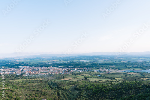 Aerial view of a village in the middle of fields and the unfocused mountains in the background on a sunny day