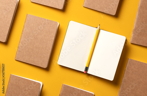 content marketing concept,.top view of hand writing on open notebook and yellow pencil align with kraft paper book in pattern on yellow table background.mockup for advertise content online