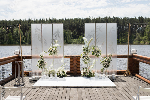 Wedding ceremony with white transparent screens and fresh flowers and candles. Wedding exit ceremony with two screens with feather and white rose