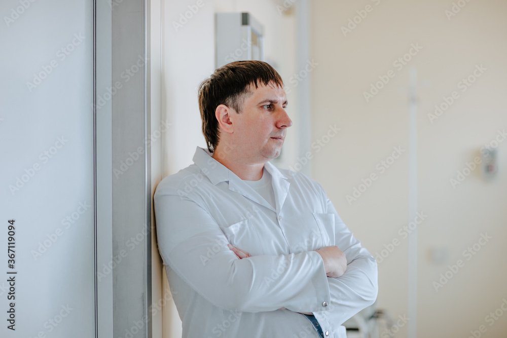 Fototapeta premium Adult handsome white doctor posing at white operation room. Copy space.