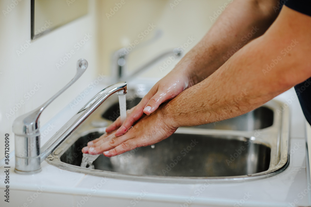 Male's doctor's hands washing with foam under the water stream. Male's doctor's hands washing with foam under the water stream.