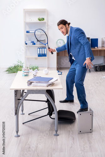 Young male employee playing tennis in the office