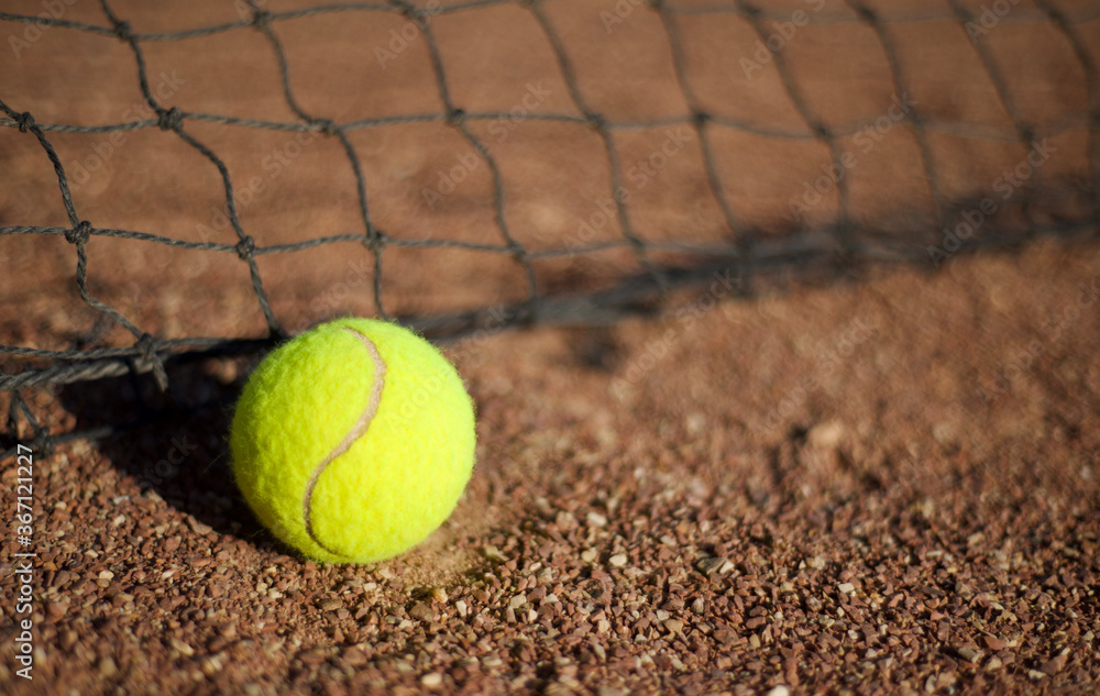  Tennis ball on clay and tennis net. Copy space for text.