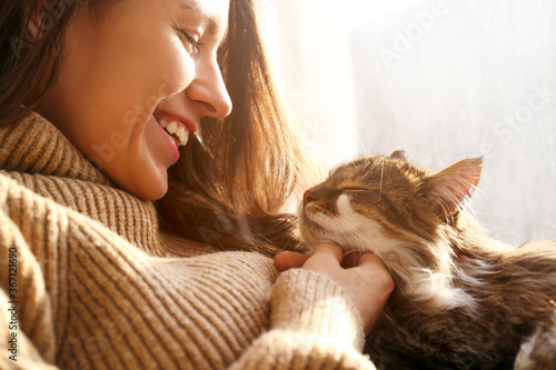 Charismatic young woman playing with her adorable cat. photo