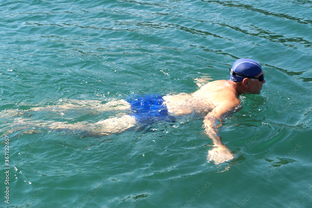 man in swimming goggles swims in the sea .