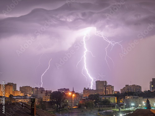 Photo of beautiful powerful lightning over big city, zipper and thunderstorm, abstract background, dark blue sky with bright electrical flash, thunder and thunderbolt.